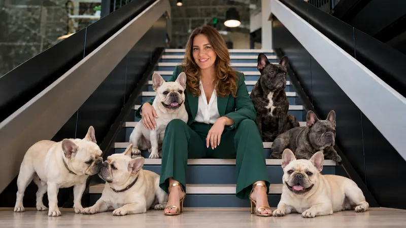 Angie Brannon seated on a staircase surrounded by her six French bulldogs